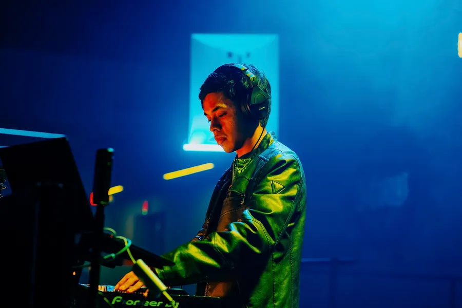DJ performing behind Pioneer DJ decks under blue and green stage lighting
